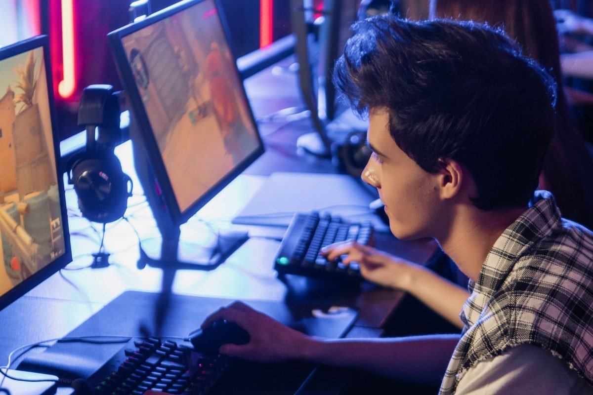 Young gamer playing at a computer with colourful lighting
