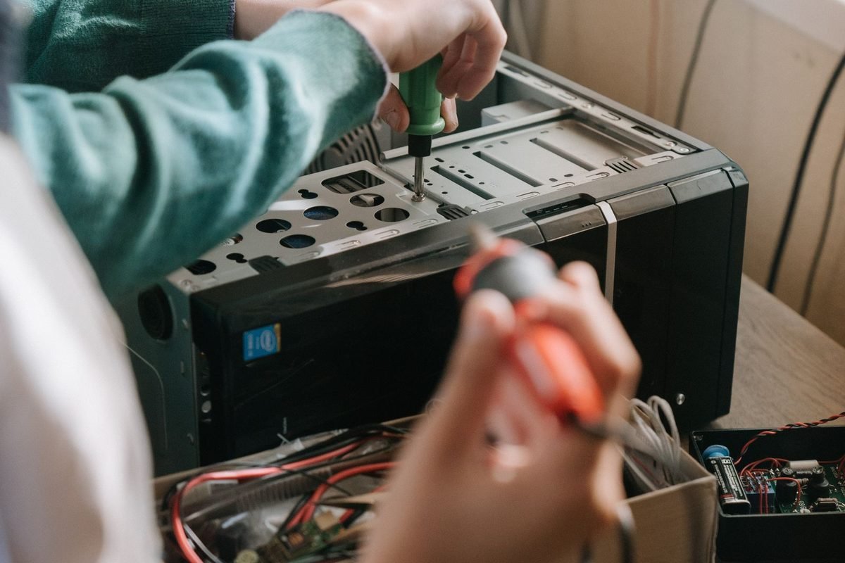 Technicians working with tools on the inside of a desktop computer