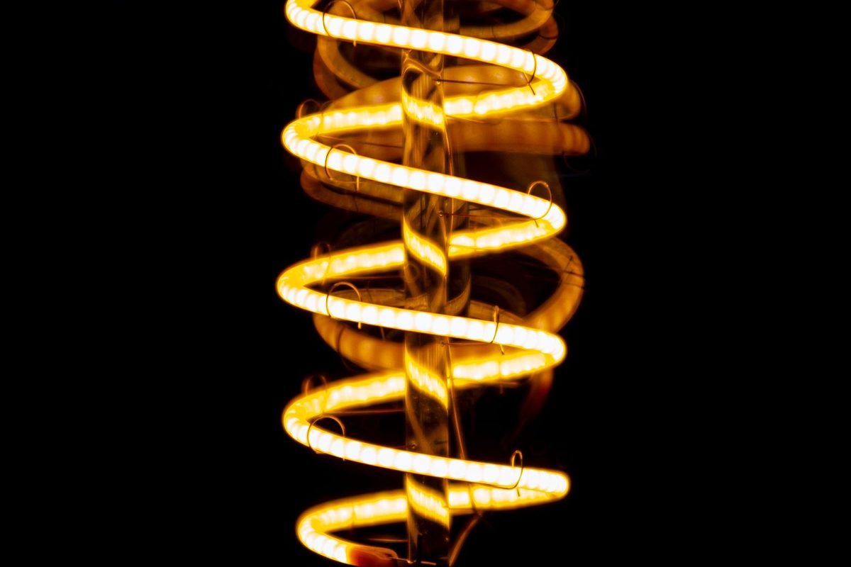 Glowing filament light bulb with a spiral wire on a black background