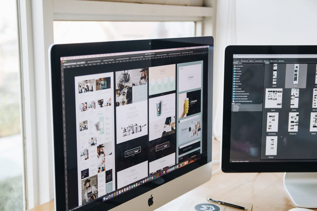 Two monitors showing design software on a desk