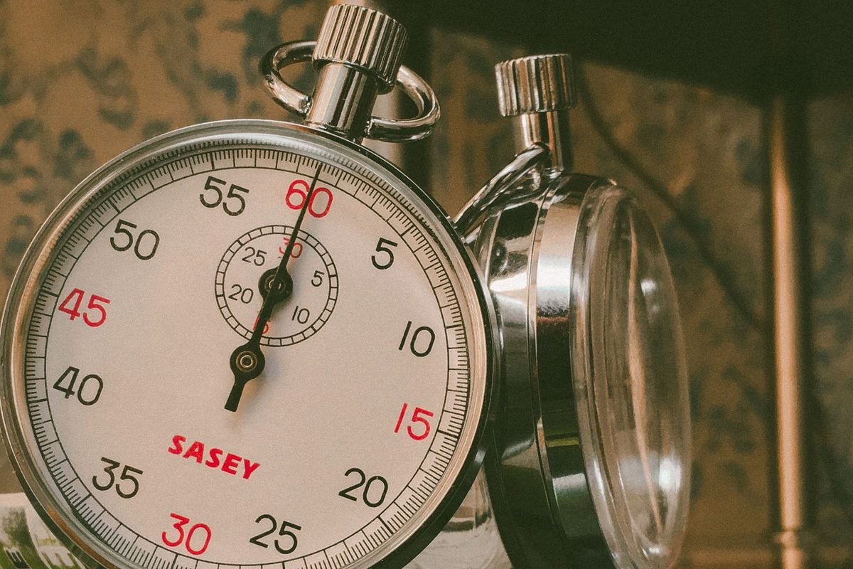 Two analogue stopwatches reflected on a glass surface