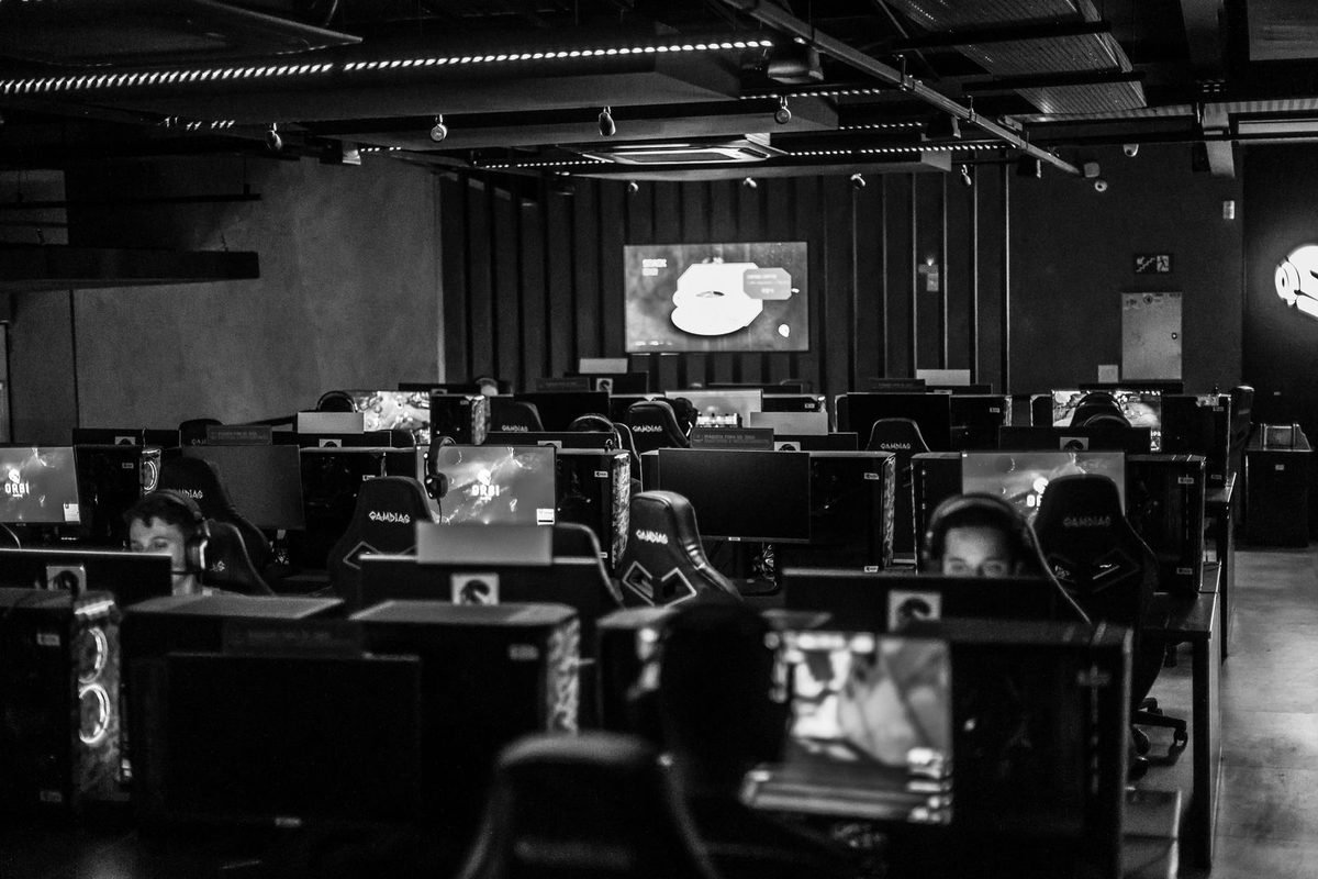 Rows of gaming computers in a dark gaming arena, shown in black and white