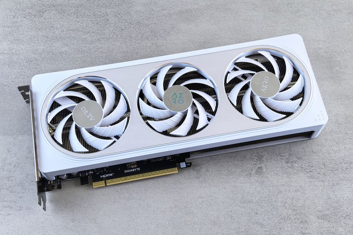 White graphics card with three cooling fans on a grey surface
