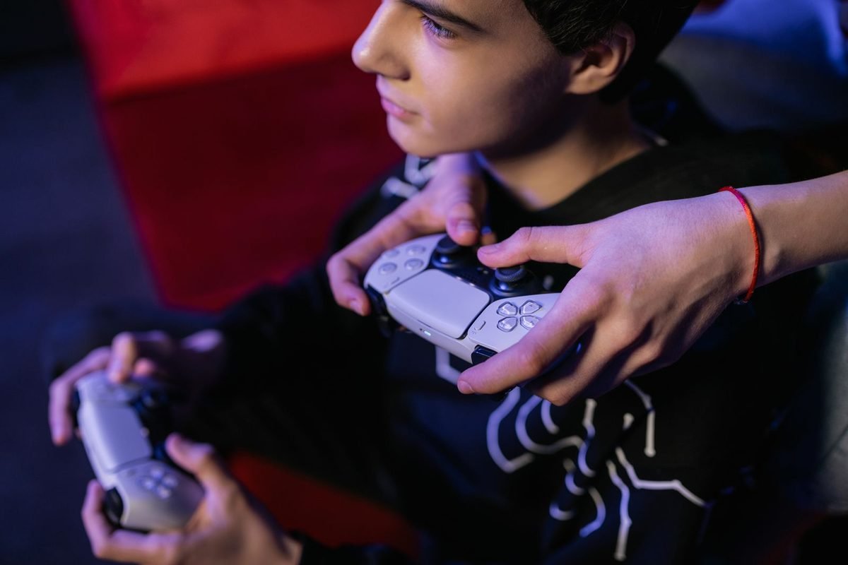 Young gamer holding two game controllers with a focused expression