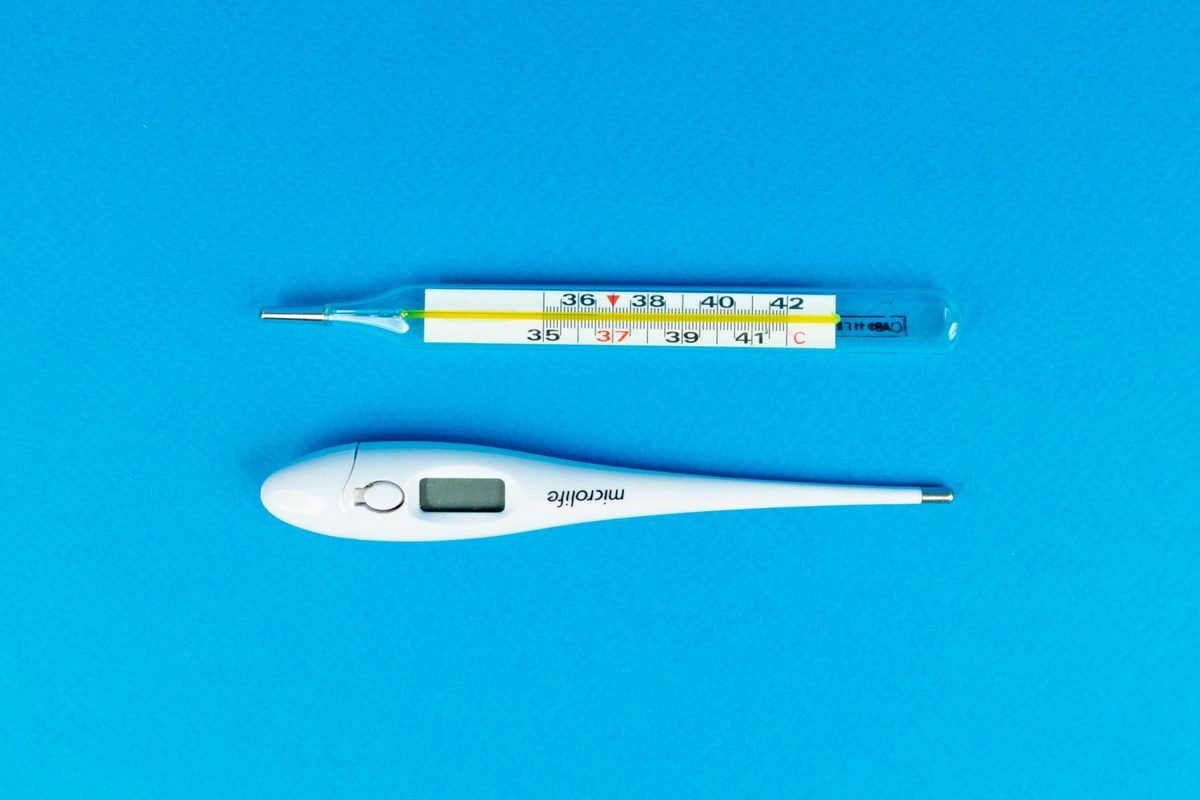 Digital and glass thermometers on a blue background