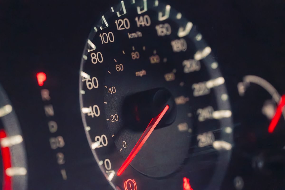 Illuminated analogue speedometer gauge in a dark car dashboard